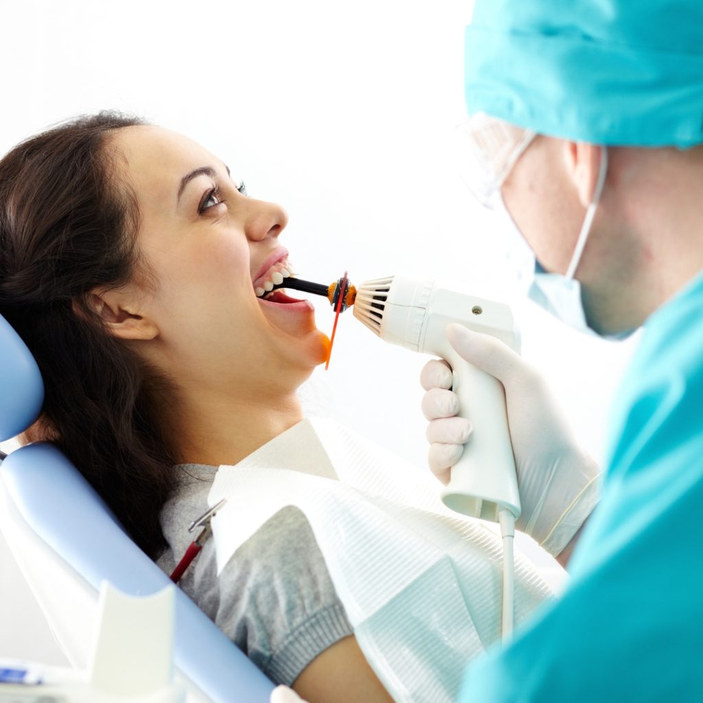 Dentist curing a filling for a smiling patient