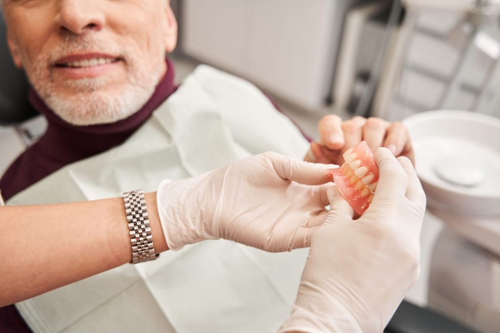 Dentist fitting a partial denture for a senior patient
