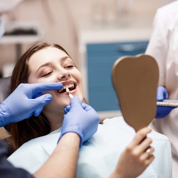 Woman smiling at her reflection after cosmetic dental treatment